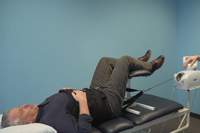 Man undergoing spinal decompression therapy on a treatment table