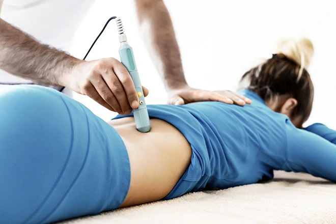Non-invasive pain therapy ultrasound on a woman's lower back.