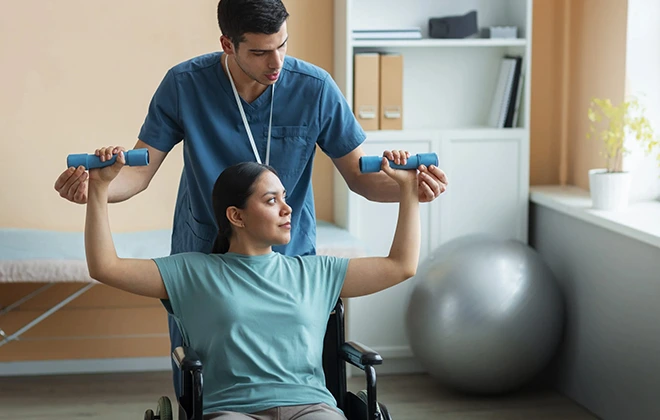 Woman in wheelchair doing chiropractic corrective exercise with physical therapist's help.