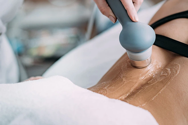 Physical therapist performing ultrasound therapy on a patient's hip with gel.