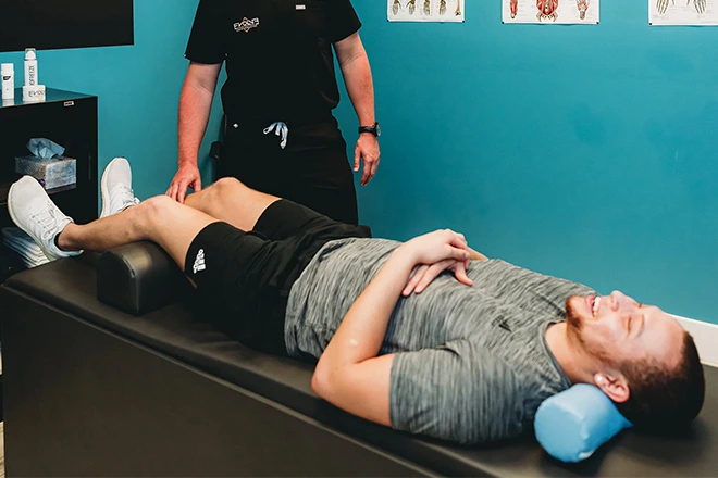 Chiropractor performing EMS therapy on a patient lying down