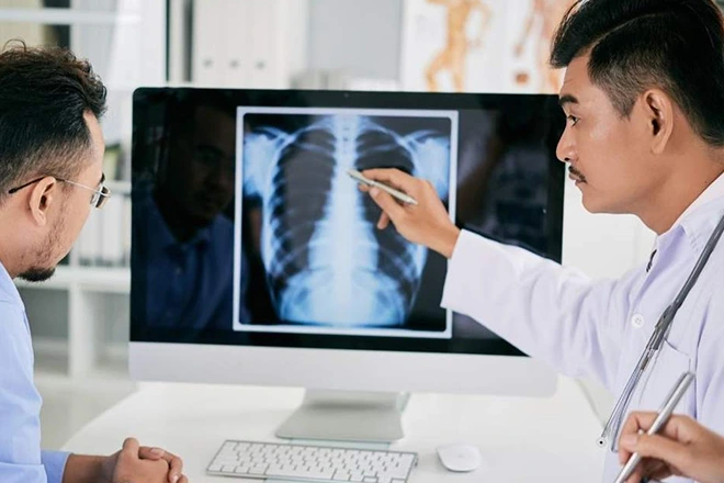 Doctor explaining back pain X-ray to patient, pointing to lungs.
