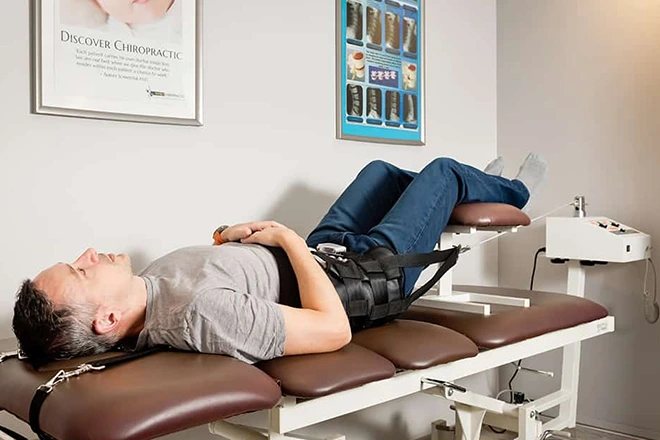 Man on spinal decompression table at chiropractic clinic for lower back pain relief.