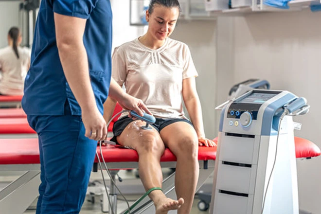 Physical therapist assisting woman with post-surgical knee treatment