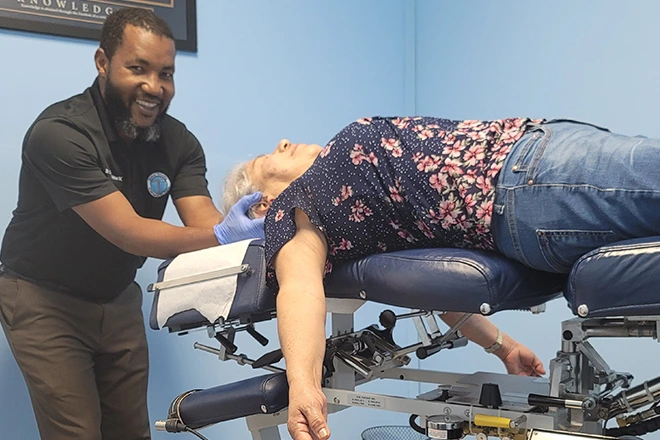 Chiropractor adjusting a senior woman's neck on an adjustment table.