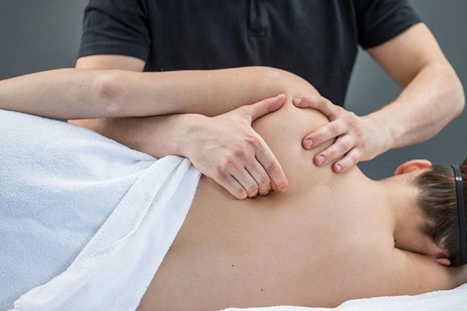 Therapist working on a patient's back and shoulder muscles.